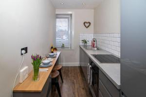 a kitchen with a table and a counter top at Am Meadhan - Comet Apartments in Helensburgh