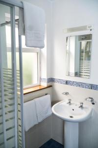La salle de bains blanche est pourvue d'un lavabo et d'une fenêtre. dans l'établissement Kerry-Lee Holiday Homes Tralee, à Tralee