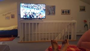 a person with their feet up on a crib watching a tv at 44 Kliffstraße in Nienhagen