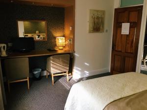 アデアにあるAbbeyvilla Guesthouse Room Onlyのベッド、デスク、コンピュータが備わるホテルルームです。