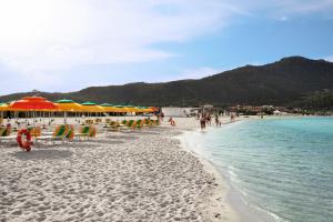 una spiaggia con sedie e ombrelloni e l'oceano di Marinella, Sardegna a Marinella