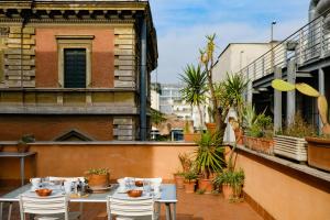 un patio con mesas y sillas en el balcón en Spacious Apartment with Big Terrace at Colosseum, en Roma