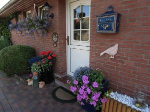 une porte menant à une maison en brique ornée de fleurs dans l'établissement Ferienwohnung Heimathafen, à Werdum