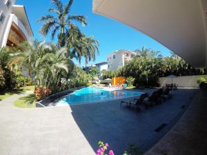 una piscina con sillas y árboles y un edificio en 3 Bedroom Apartment at La Joya Hotel Zone, en Puerto Vallarta