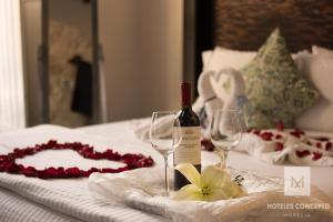 a bed with a bottle of wine and two wine glasses at M Hoteles Concepto in Morelia