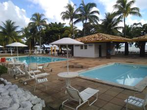 a swimming pool with chairs and a table next to a resort at Apto condomínio Jubiabá in Olivença