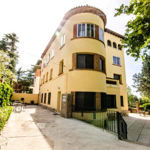 ein großes gelbes Gebäude mit einem Zaun davor in der Unterkunft Fuente Torán Apartamentos in Teruel