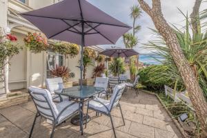 a patio with a table and chairs and an umbrella at Lindum Lodge in Torquay