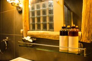 Baño con 3 botellas en un estante y espejo en Cerulean View Residence, en Hanimaadhoo
