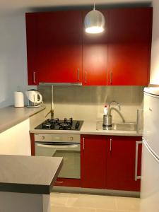 a kitchen with red cabinets and a sink at Apartament Centrum Jana Pawła II in Warsaw