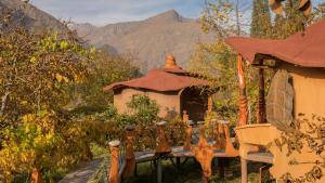 a table in front of a building with mountains in the background at Cascada Lodge Cajon del Maipo in San José de Maipo