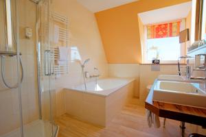 ein Badezimmer mit zwei Waschbecken, einer Badewanne und einer Dusche in der Unterkunft Hotel Am Badepark in Bad Zwischenahn