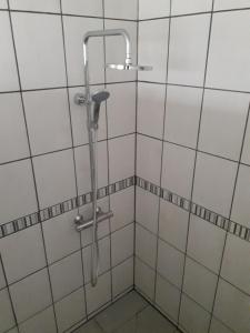 um chuveiro na casa de banho com azulejos brancos em Les Peupliers em Vesly