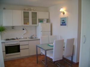 cocina con armarios blancos, mesa y sillas en Apartmani A1 Marina, Okrug Gornji en Trogir