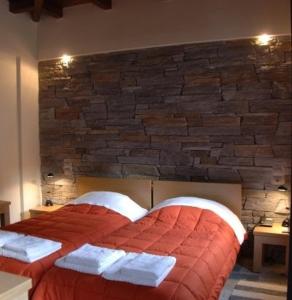 a bedroom with a red bed with a brick wall at Thalia Rooms in Kalabaka