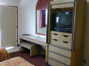 a room with a tv and a dresser with a mirror at Umatilla Inn & Suites in Umatilla