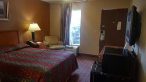 a hotel room with a bed and a chair and a window at Scottish Inn Knoxville in Knoxville