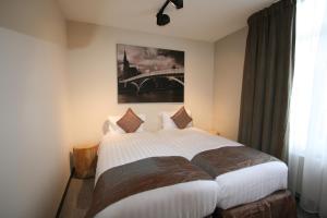 a bedroom with a white bed with a painting on the wall at Amosa Liège City Centre Apart Regence 17 in Liège
