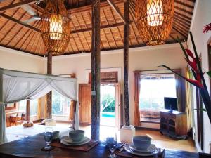a dining room with a table and chandeliers at Thani Villa Ubud in Ubud