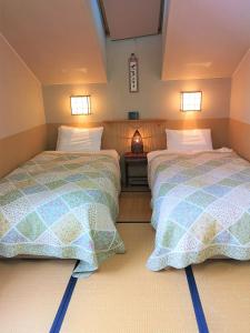 two beds in a small room at Pension Raclette in Nakafurano