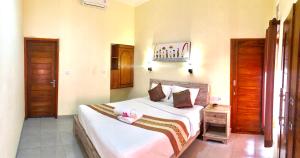 a bedroom with a large bed with a pink pair of shoes on it at D'Waktu in House in Nusa Lembongan