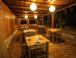 un restaurante con mesas de madera, sillas y luces en Hotel Navego, en Lobitos