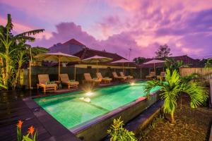 a swimming pool with patio furniture and umbrellas at Samanta Huts in Nusa Lembongan