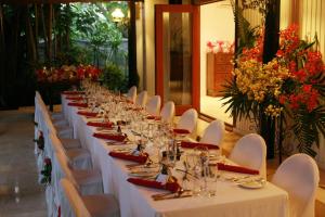 una mesa larga con mesas blancas, sillas y flores en The Fiji Orchid en Lautoka