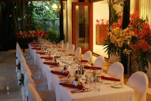 einen langen Tisch mit weißen Tischen, Stühlen und Blumen in der Unterkunft The Fiji Orchid in Lautoka