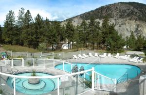 vistas a una piscina con sillas y a la montaña en Kumsheen Rafting Resort, en Lytton