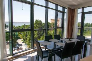 uma sala de jantar com mesa e cadeiras e janelas grandes em Riviera Residence Apartments em Mamaia