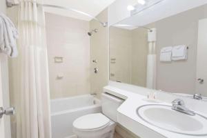 a bathroom with a sink and a toilet and a mirror at Howard Johnson by Wyndham Vero Beach / Downtown in Vero Beach