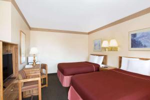 a hotel room with two beds and a flat screen tv at Howard Johnson by Wyndham Brigham City in Brigham City