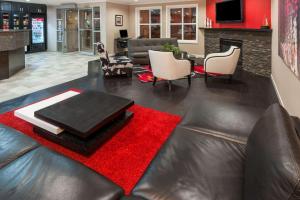 a living room with a leather couch and a red rug at Ramada by Wyndham Sherwood Park in Sherwood Park