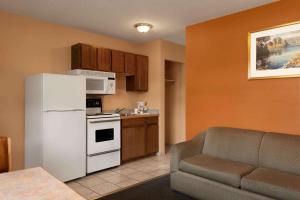 a kitchen with a white refrigerator and a couch at Travelodge by Wyndham Quesnel BC in Quesnel