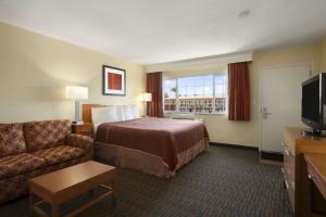 a hotel room with a bed and a couch and a television at Howard Johnson by Wyndham San Diego Sea World in San Diego
