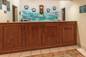 a large wooden counter in a room with clocks on the wall at Howard Johnson by Wyndham Airport in Louisville