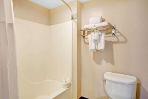 y baño con aseo y ducha con toallas. en Howard Johnson by Wyndham Galveston, en Galveston