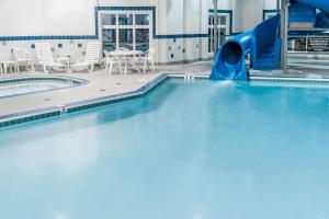 a pool with a water slide in a building at Ramada by Wyndham High River in High River