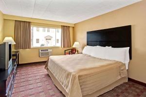 a hotel room with a bed and a television at Howard Johnson by Wyndham Pikesville in Pikesville
