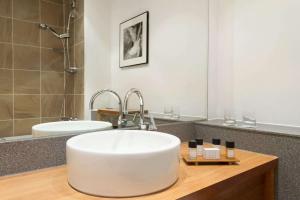 a white sink sitting under a mirror in a bathroom at Ramada Plaza Wrexham in Wrexham