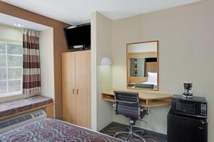 a hotel room with a desk and a bed and a mirror at Microtel Inn by Wyndham University Place in Charlotte