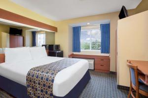 um quarto de hotel com uma cama grande e uma secretária em Microtel Inn & Suites Leesburg em Silver Lake