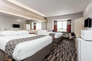 a hotel room with two beds and a flat screen tv at Microtel Inn & Suites Modesto in Ceres +12 photos