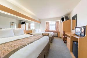 a hotel room with two beds and a television at Microtel Inn & Suites by Wyndham Altus in Altus