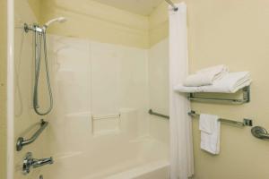 a bathroom with a tub and a shower with towels at Microtel Inn & Suites by Wyndham Auburn in Auburn