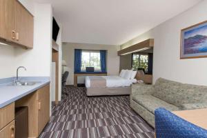 Baymont Inn & Suites by Wyndham Anchorage Airport في أنكوراج: غرفه فندقيه بسرير واريكه