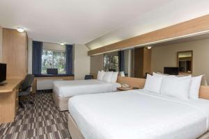 a hotel room with two beds and a desk at Baymont Inn & Suites by Wyndham Anchorage Airport in Anchorage