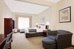 a hotel room with a bed and a chair at Wingate by Wyndham Destin in Destin