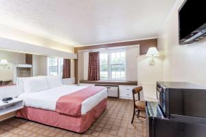 a hotel room with a bed and a flat screen tv at Microtel Inn by Wyndham Wilson in Wilson